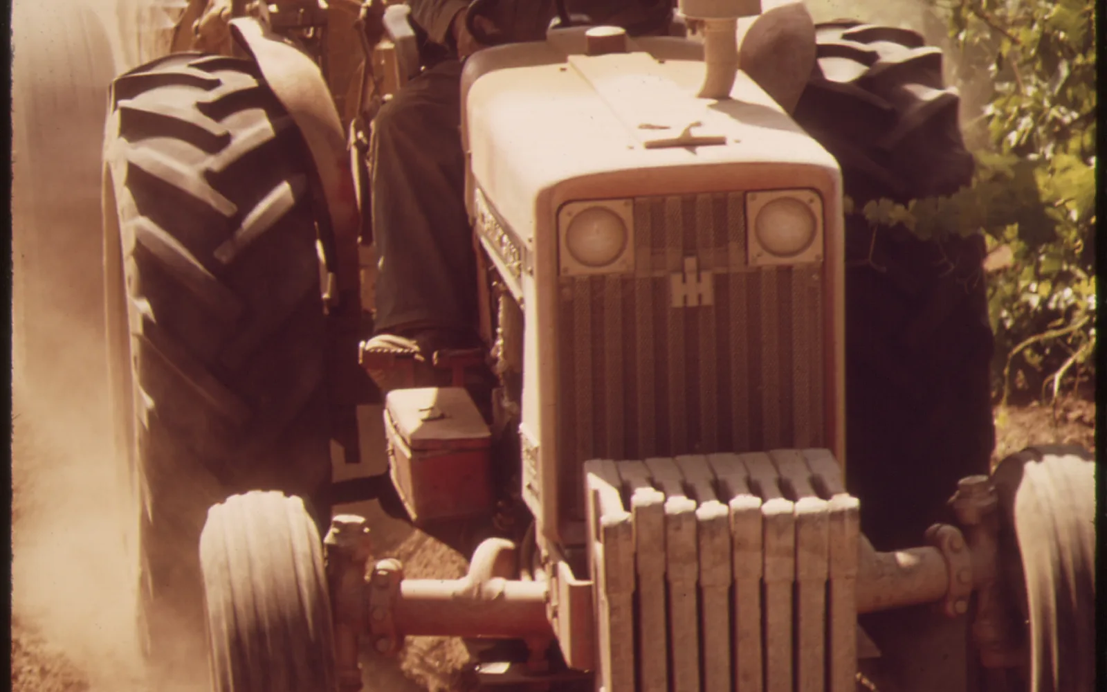 Tractor with sprayer applying crop protection to grape vines in a California vineyard